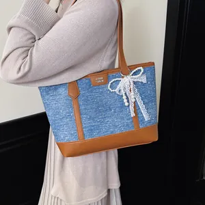 Détail d'un sac cabas en denim bleu orné d'un nœud en dentelle blanche et de perles