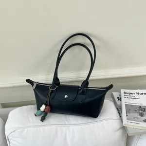 Gros plan d'un sac à main noir minimaliste avec breloque perlée colorée sur un coussin