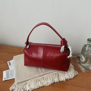 Close-up detail of glossy red pillow handbag featuring oversized silver metal link