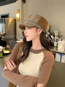 Stilvolles asiatisches Model mit braun karierter britischer Retro-Bäckermütze im Café.
