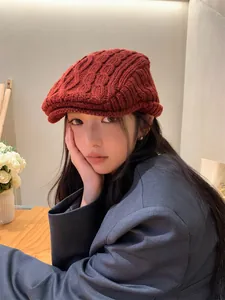 Close-up of women's vintage rust-red cable knit flat cap for winter warmth.