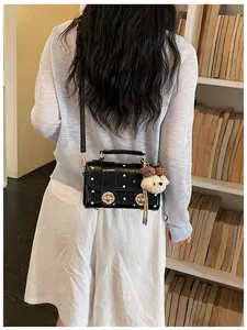Detail view of vintage black polka dot crossbody bag on model in cozy library setting.