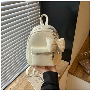 Detailansicht eines schicken cremefarbenen Mini-Rucksacks mit modischem Schleifenanhänger