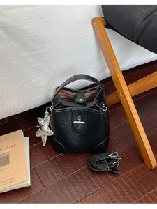 Vue détaillée d'un sac seau en cuir grainé noir vintage avec un pendentif étoile argenté.