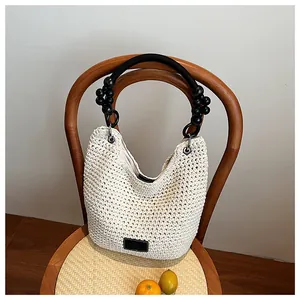 Detailed view of a stylish handwoven bucket bag with black beaded handle on a chair