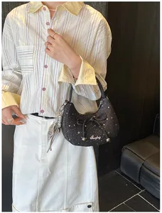 Black hobo bag with bow and star pattern worn by a model in a chic outfit