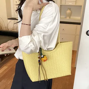 Primer plano de bolso tote tejido amarillo con colgante en un ambiente de estilo