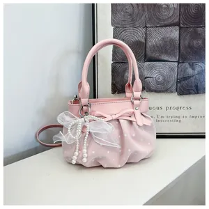 Detailed shot of the pink pleated bucket bag featuring polka dots and a pearl bow accent