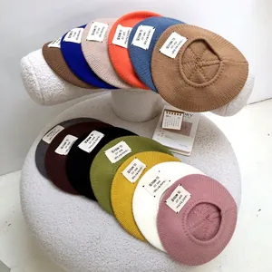 Detail view of colorful knitted wool berets with vintage letter patch designs