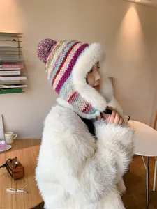 Detailed view of a colorful striped knitted trapper hat with plush white faux fur trim.