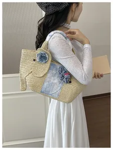Détail du sac à main en paille tressée éléphant avec ornements floraux et tie-dye