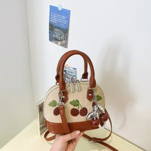 Detalle del bolso de lona beige con bordado de cerezas y colgante de perlas