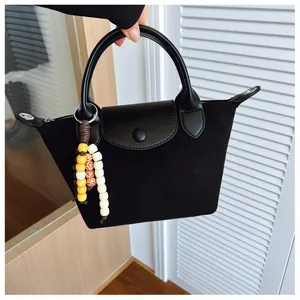 Gros plan d'un sac à main noir en daim de type dumpling avec un charm décoratif en perles colorées