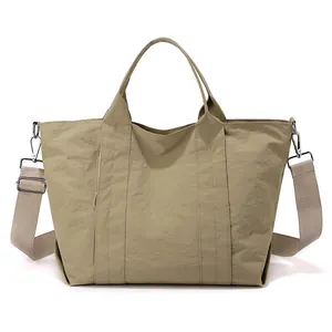 Vista frontale di una grande borsa tote in nylon kaki con tracolla regolabile e ampia