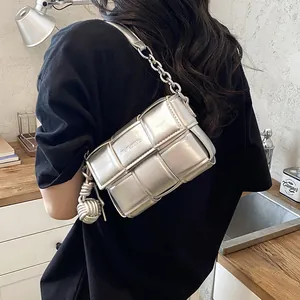 Detail of silver metallic woven square bag with chunky chain strap and knot charm