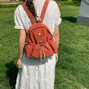 Vista trasera detallada de un vestido blanco con una mochila naranja óxido con cordón