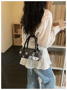 Fashion model carrying a black cylinder handbag with cute cartoon cat prints and blue bow charm
