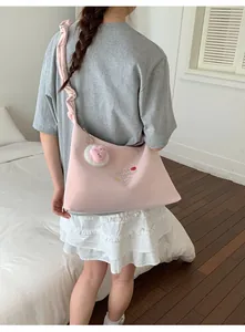 Detalle del bolso bandolera rosa dulce con correa fruncida y colgante de amuleto