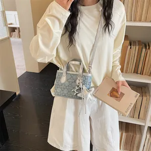 Lifestyle shot of a stylish blue denim mini bucket bag with silver charms and strap