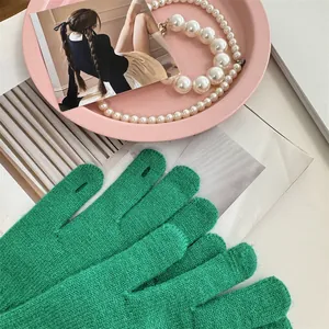 Detailed view of green knitted winter gloves with touch-screen finger opening