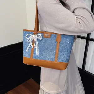 Détail d'un sac cabas en jean élégant avec nœud en dentelle et perles sur le côté