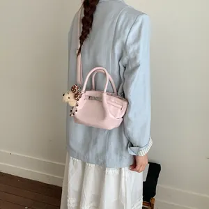 Vista dettagliata di una mini borsa rosa alla moda con ciondolo di peluche su modella