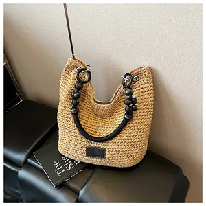 Close-up of a woven straw bucket bag with elegant black beaded handles and texture