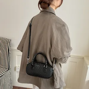 Schwarze Tasche mit Webmuster am Modell mit Schultergurt für einen lässigen Look