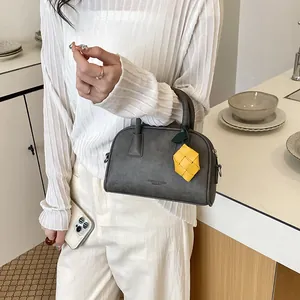 Detail of a grey pillow bag with a yellow charm in a minimalist kitchen setting