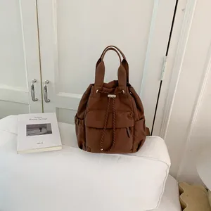 Primer plano de una mochila marrón con cordón, bolsillos laterales y correas resistentes.