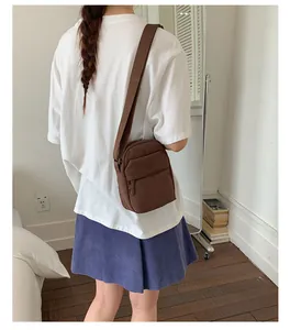 Simple brown crossbody mobile phone bag for women shown on a model in a bedroom setting.