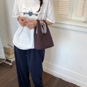 Nahaufnahme einer Frau mit einer stylischen braun karierten Mini-Beuteltasche für den Alltag