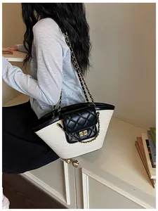 Détail du sac cabas en paille tissée avec rabat matelassé noir et chaîne dorée.