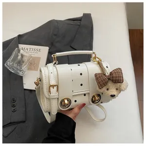 Detailed view of a retro white polka dot handbag featuring a cute teddy bear plush charm