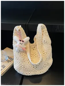 Primo piano della borsa tote in paglia beige all'uncinetto con un grazioso portachiavi a coniglio
