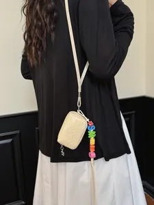 Elegant cream mini crossbody bag featuring colorful letter beads and embossed text