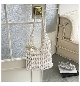 Bolso de hombro de punto calado beige con colgante de tulipán colgado en una puerta