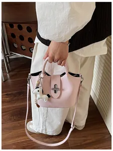 Détail d'un sac seau rose porté à la main avec un joli accessoire de breloque de cheval blanc