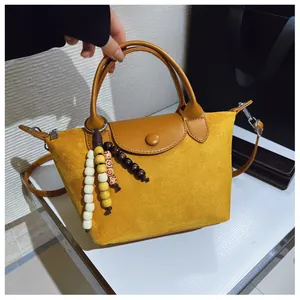 Détail de la texture en daim jaune et des breloques perlées sur un petit sac à main