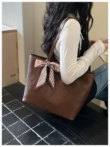 Lifestyle view of a woman wearing a brown textured leather tote bag with silk scarf detail