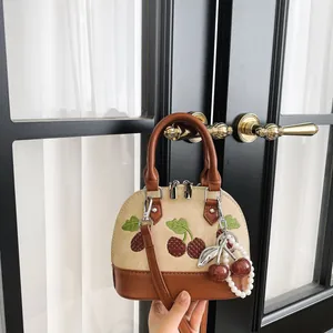 Elegante bolso de mano beige y marrón con bordado de cerezas y colgante de perlas