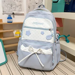 Detail of cute light blue student backpack with star patterns and bow decoration.