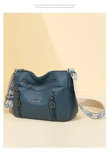 Blue pebbled leather crossbody bag with multi-zip design and patterned strap detail.