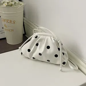 White pleated handbag with black polka dots placed next to flower bucket decoration