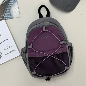 Detalle de una mochila de exterior morada y gris con bolsillos de malla y cordones elásticos.
