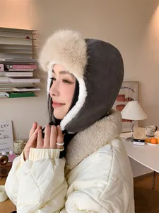 Side view of woman wearing grey corduroy plush earflap hat with soft fur lining