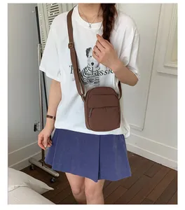 Small brown crossbody square bag for women worn by a model in a casual indoor setting