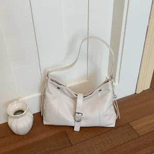 Minimalist white faux leather shoulder bag with silver buckle detail on wooden floor
