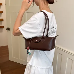 Vue détaillée d'un sac dumpling sous l'aisselle en cuir marron foncé porté par un mannequin