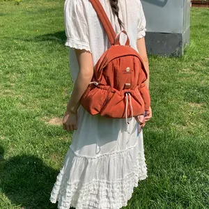 Elegante mini mochila naranja quemado en modelo con vestido blanco al aire libre